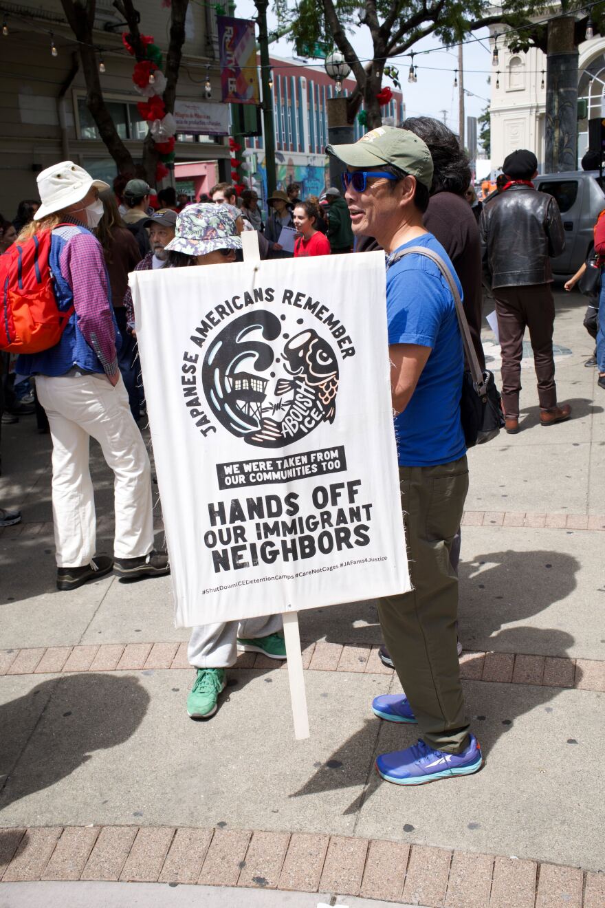 Scott Hoshida of Oakland holds a sign at the Fruitvale Village May Day rally. Hoshida’s sign is a reflection the history of Japanese internment during the Second World War.