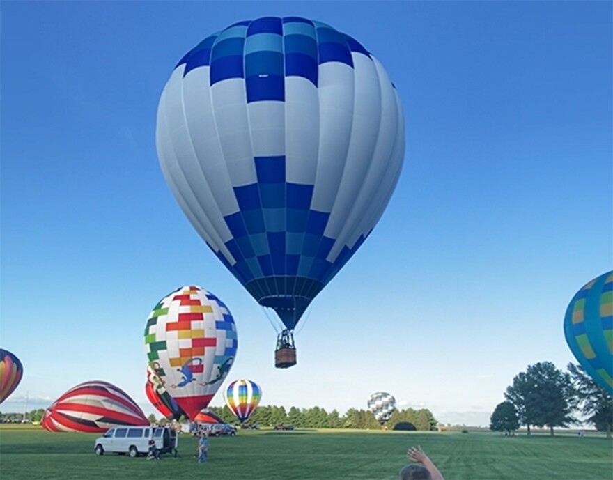  hot air balloon flies, with others behind it