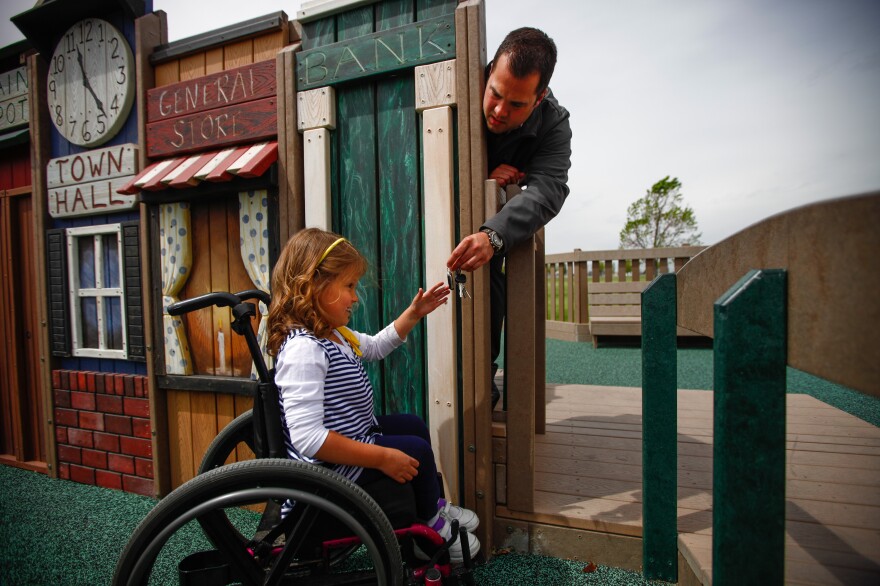 Brooklyn Fisher, who has spina bifida, plays with her father, Jonny Fisher, at the playground.