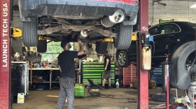 A mechanic stands under a vehicle on a lift 