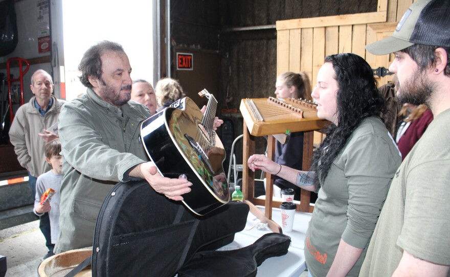 Michael Jonathan, host of WoodSongs Old Time Radio Hour, offers a guitar during the instrument giveaway in Dawson Springs.