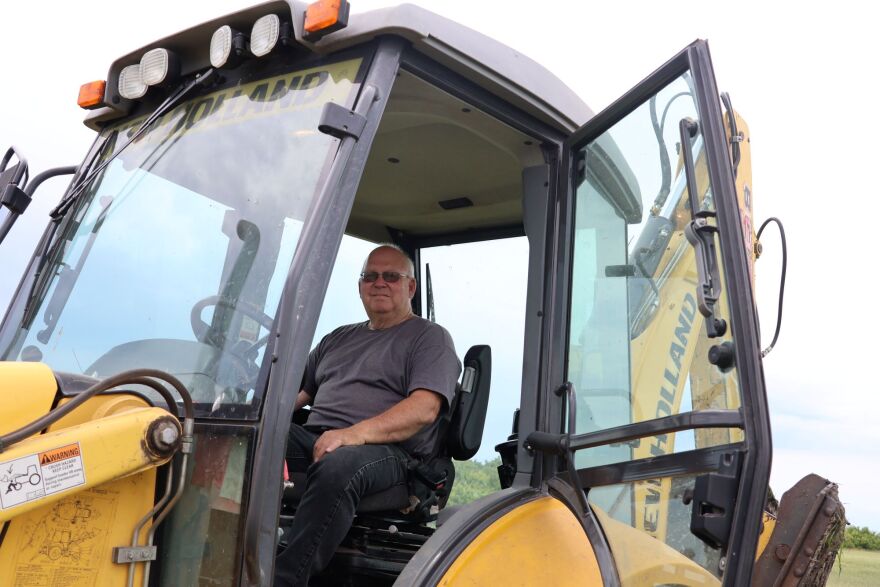 An older man sits inside an excavator after doing fieldwork