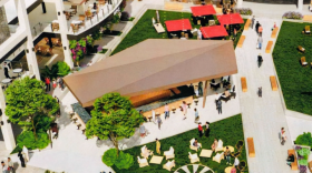 An overhead rendering of the new courtyard bar. A large canopy is over the bar in the middle of the courtyard next to a two story building. Small picnic tables with canopies above them behind the large tent.