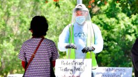 A volunteer dressed in full protective gear gives directions to a woman at a walk-in COVID-19 test site in Los Angeles, California. 