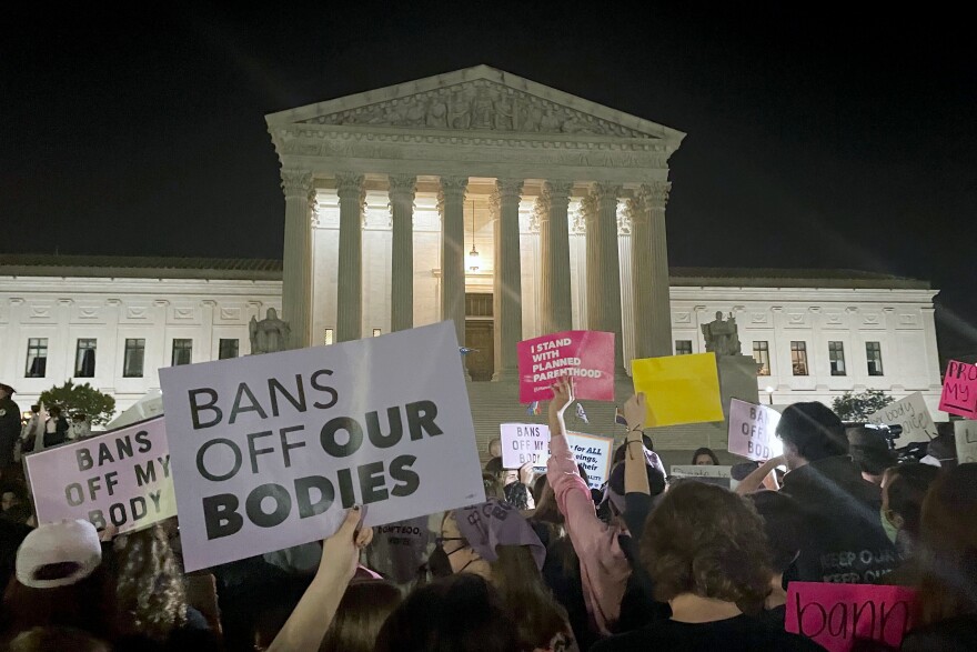 A crowd of people gather outside the Supreme Court, Monday night, May 2, 2022 in Washington. A draft opinion circulated among Supreme Court justices suggests that earlier this year a majority of them had thrown support behind overturning the 1973 case Roe v. Wade that legalized abortion nationwide, according to a report published Monday night in Politico.