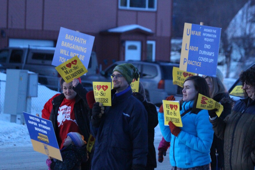 people in winter jackets wave signs