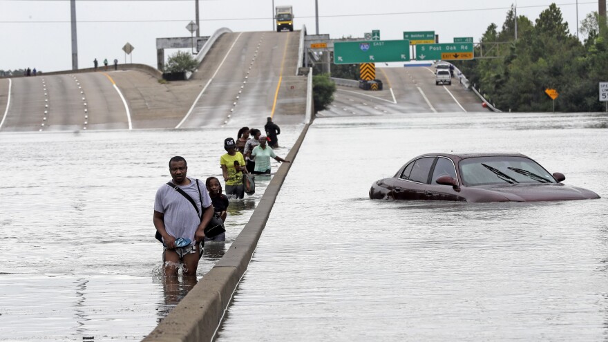 Residents of southeast Texas are taking stock and trying to absorb record flooding brought by Hurricane Harvey. Here, evacuees wade down a flooded section of Interstate 610 in Houston as floodwaters continued to rise Sunday.