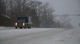 A blue ambulance drives on a snow covered road.
