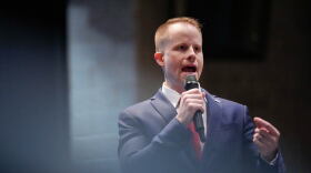 A man in a suit speaks into a microphone.