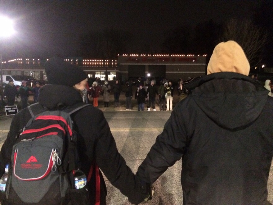 Protesters link hands for a moment of silence in the street in front of the Ferguson Police Department on Wednesday, March 4, 2015.