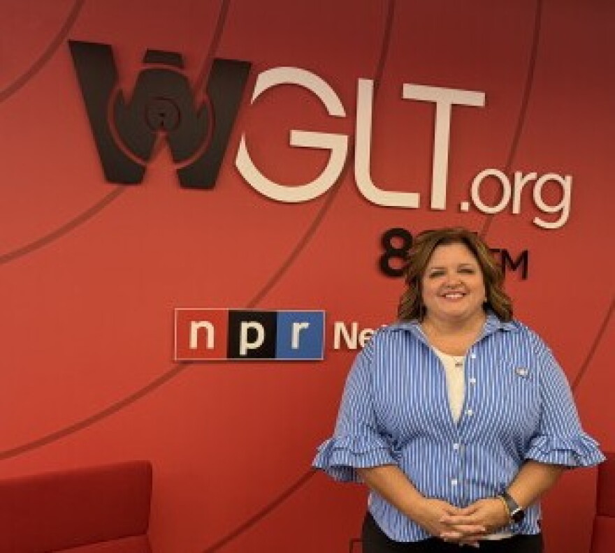 Woman stands in front of WGLT|NPR mural.