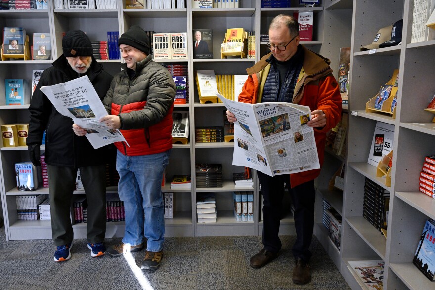 Standing in a local bookstore, Andy Thibault, Editor and Publisher of The Winsted Citizen, left, looks over the paper's first issue with town planner Lance Hansen, center, as Winsted economic development director Ted Shafer, right, looks over his own copy, Friday, Feb. 3, 2023, in Winsted, Conn.