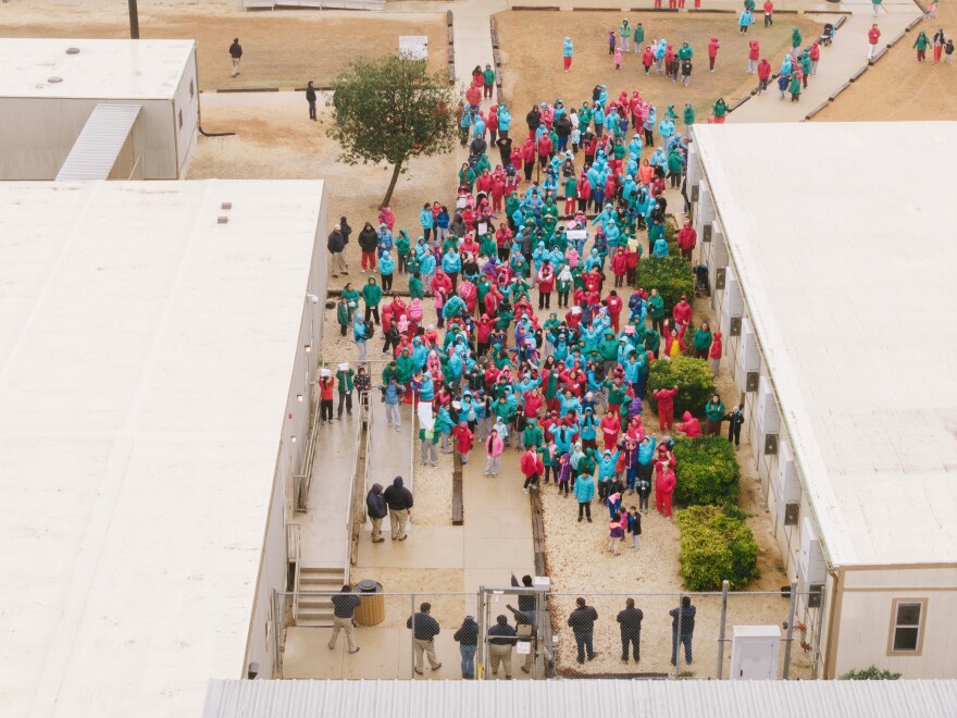 Detainees held at the South Texas Family Residential Center wave signs during a demonstration in Dilley, Texas, Saturday, Jan. 24, 2026.