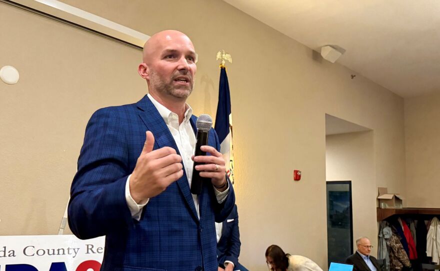 A man in a blue suit is holding a microphone at an event.