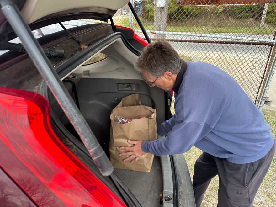 A person loads a bag of food into the trunk of their car
