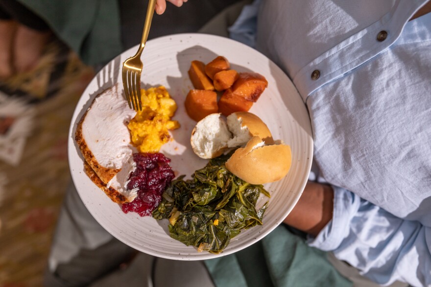 A person standing holds a plate of Thanskgiving food 