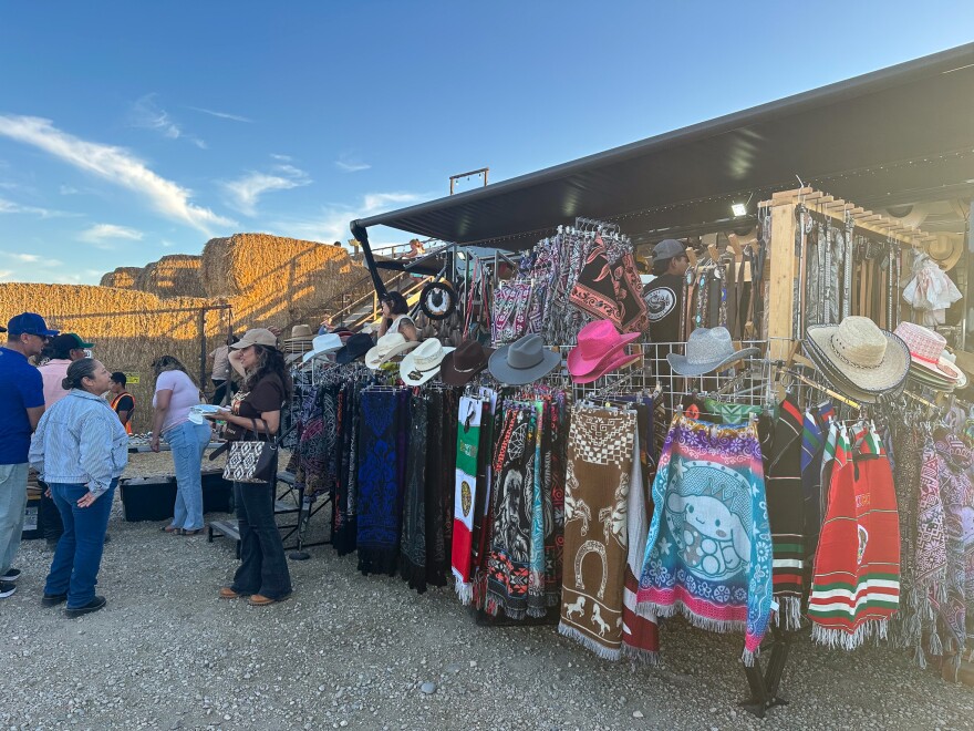 People tanding talking near a vendor of sarapes and cowboy hats