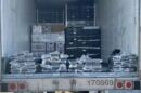 A photo of the interior of a refrigerated box truck containing packages of cocaine stacked at the edge of the opening