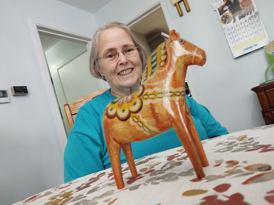 Virginia Weygandt, Clark County Heritage Center curator emeritus, looks and smiles at a wooden horse on a table in front of her.