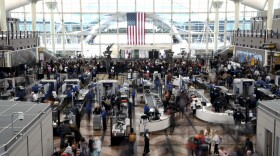 Passengers wait in a security line at Denver International Airport on Feb. 22, 2023. Passengers had to use an emergency slide to evacuate a smoking American Airlines jet at Denver International Airport. The Federal Aviation Administration says the Boeing 737 MAX 8 reported a "possible landing gear incident" during its departure for Miami on Saturday.