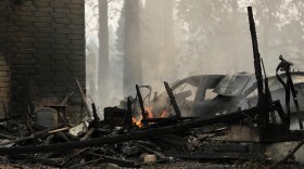 A house on N. Victor St. and W. Lyons Ave. burned by a wildfire smolders, Sunday, Aug. 2, 2026, in Spokane, Wash. 