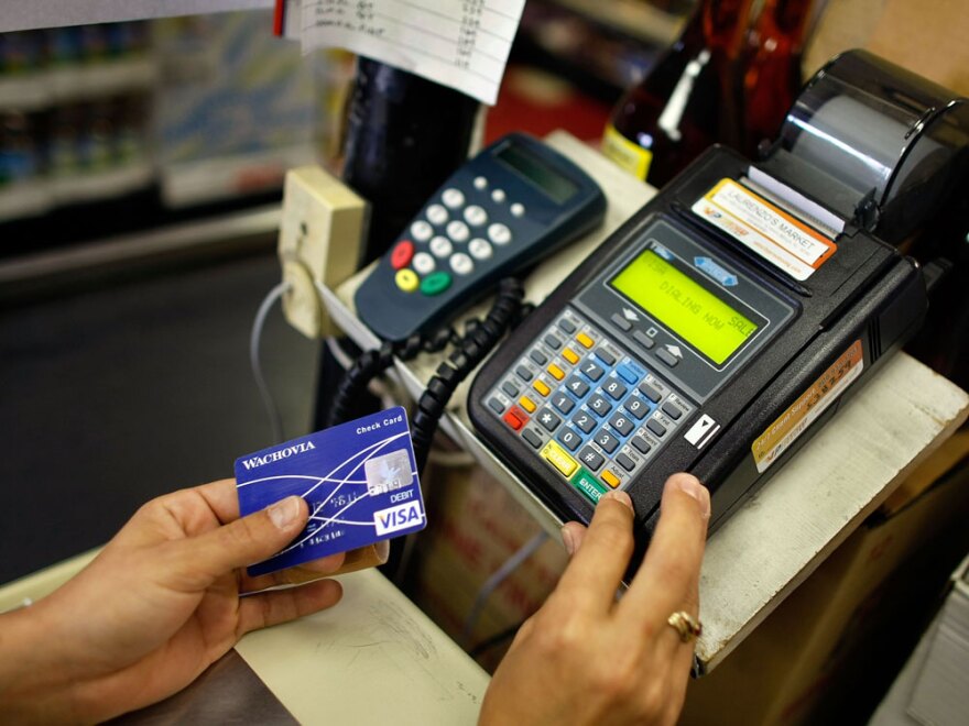 Yera Dominguez uses a credit card reader to charge a customer's credit card for payment last May at Lorenzo's Italian Market in Miami.