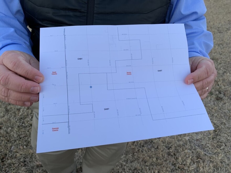 Joey Bahr holds a map that shows how close his home is (represented by a blue dot) to a neighboring internet service area that offers cable broadband.