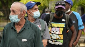 Todd Dowd, foreground, waits in line to receive the Johnson & Johnson vaccine, Thursday, May 13, 2021, at a mobile vaccination site at the Greater Bethel Church in Miami. The Miami-Dade County Homeless Trust and the Florida Division of Emergency Management partnered to provide the one-dose vaccine at unsheltered homeless hotspots and shelters across the county. (AP Photo/Wilfredo Lee)