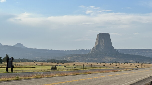 Devils Tower rises in the background, with a road in the foreground.