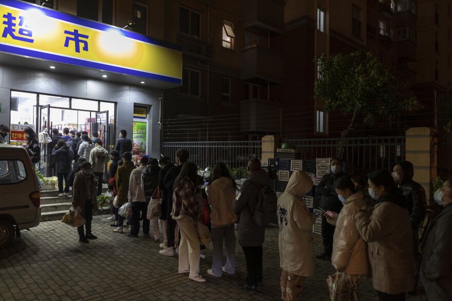 Residents line up outside a supermarket Sunday night to buy groceries in Shanghai, which is seeing lockdowns as part of China's strict anti-COVID strategy.