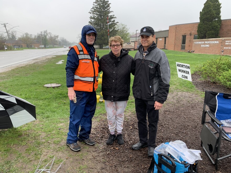 John Ryan, (left) Mary Griffin and Rich Mantoan hand out literature and place signs opposing abortion near the Planned Parenthood property.