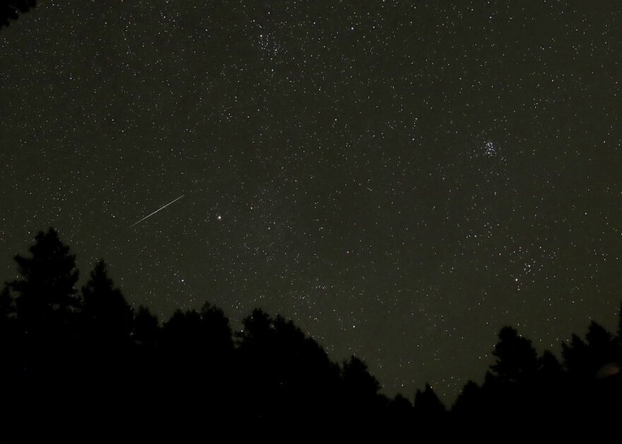 In this 20-second exposure, a meteor streaks across the night sky above trees near Moscow, Idaho in the early hours of Tuesday, Aug. 14, 2018 during the Perseid Meteor Shower. The annual event can produce dozens of meteors an hour. (AP Photo/Ted S. Warren)