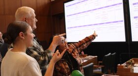 Rep. Paul Evans, D-Monmouth, (center), Chief of Staff Jennifer Randstrom-Smith (right) and Intern Emma Swartzfager (left) point at the candidate filing presentation.