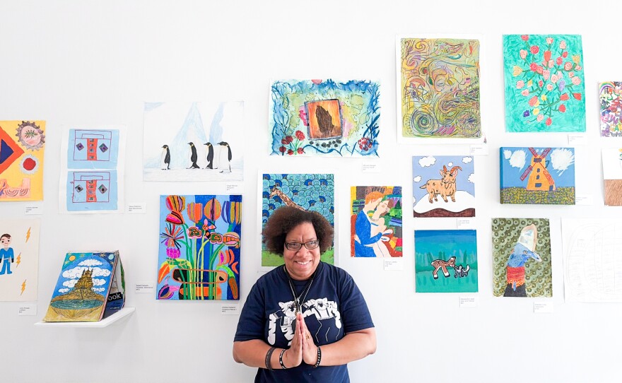 Michelle, an artist at Starlight Studio, stands posing below her artwork.