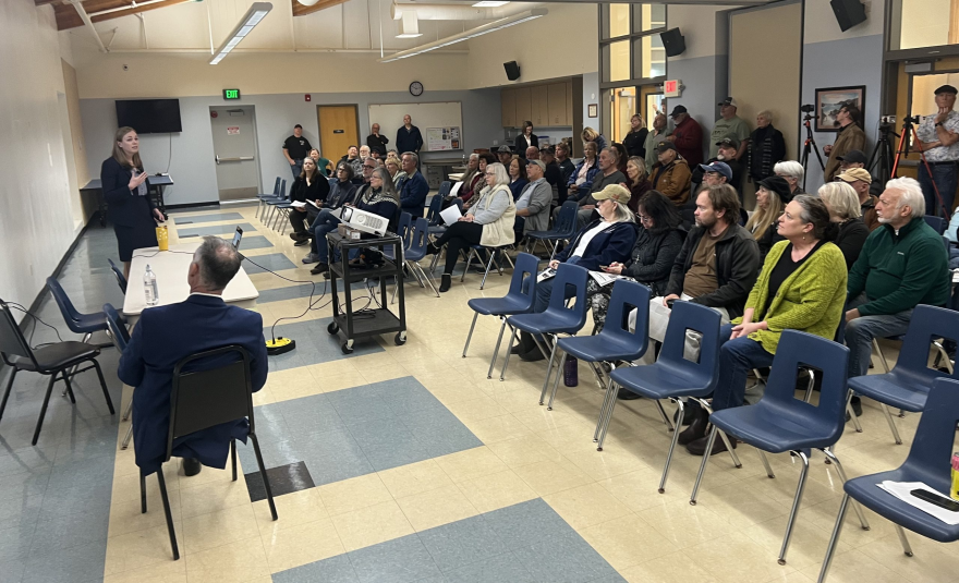 Speakers address a crows of people seated in chairs.