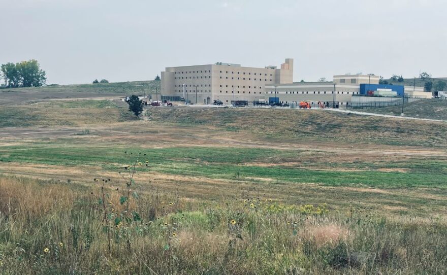 There is a large building nestled into a series of rolling hills.