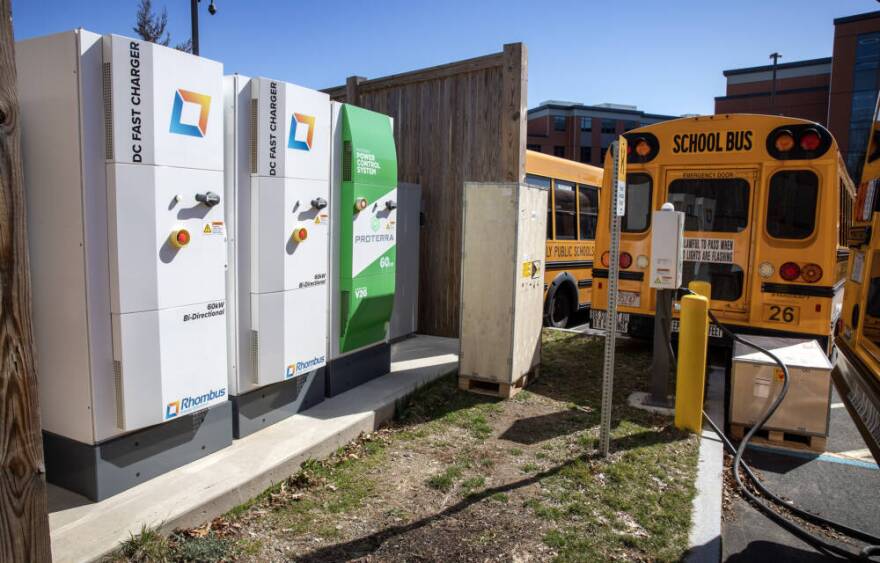 Three 60kW bi-directional chargers stand in the school bus parking lot in Beverly, Mass. (Robin Lubbock/WBUR)