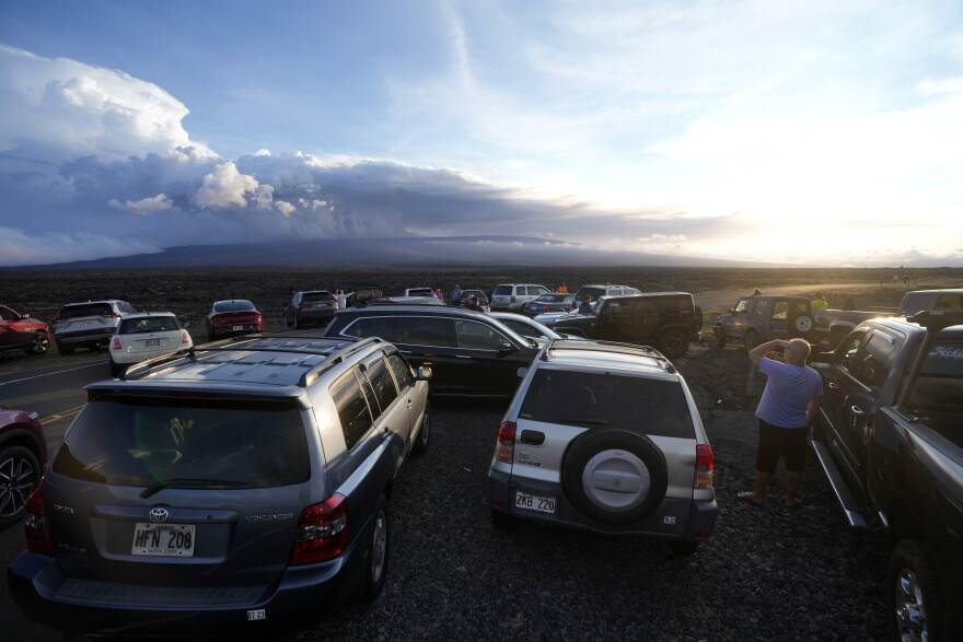 An overflow of cars sit in a parking lot near the Maunaloa volcano as it erupts Wednesday, Nov. 30, 2022, near Hilo, Hawaiʻi.