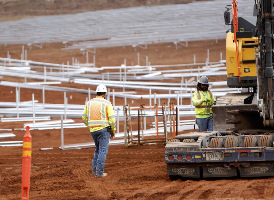 Construction crews work on unfinished racks for solar panels at the AES Corporation's West Oʻahu solar farm in Kapolei, Hawaiʻi, Tuesday, Aug. 23, 2022. (AP Photo/Caleb Jones)