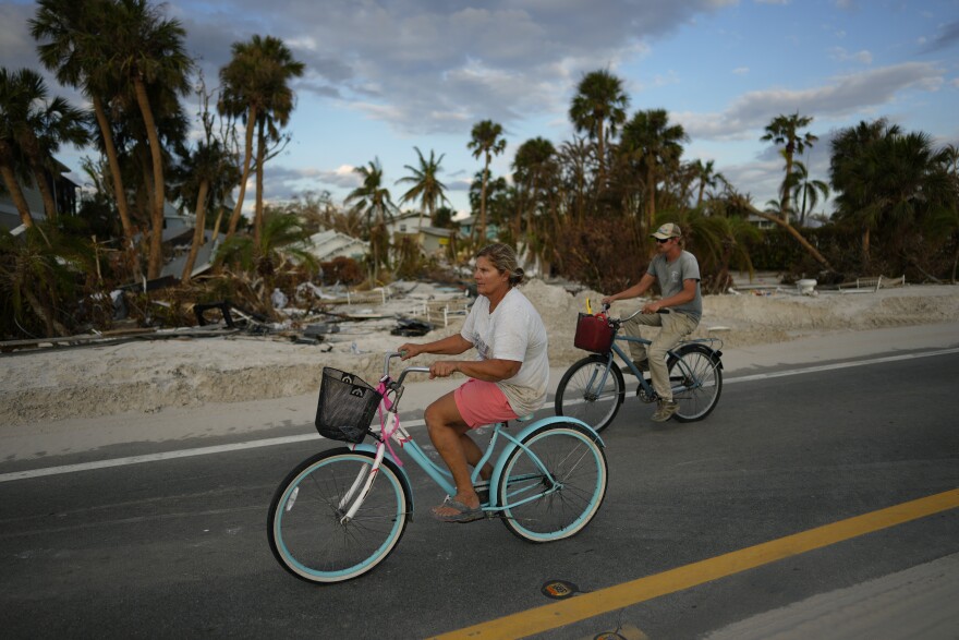 Residents remaining on Estero Island bike past debris and lots devoid of homes, one week after the passage of Hurricane Ian, in Fort Myers Beach, Fla., Wednesday, Oct. 5, 2022. (AP Photo/Rebecca Blackwell)