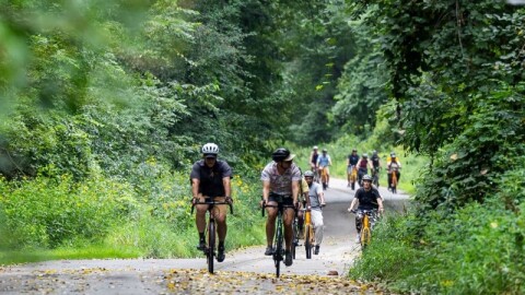 A group of cyclists bike on a paved trail along Indian Mounds Drive