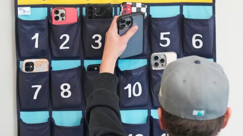 FILE - A ninth grader places his cellphone into a phone holder as he enters class at Delta High School, Friday, Feb. 23, 2024, in Delta, Utah. (AP Photo/Rick Bowmer, file)