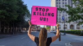 In this June 2020 file photo, Greensboro resident Candace Clapp heads toward the Greensboro protest for George Floyd with sage and sign in hand.