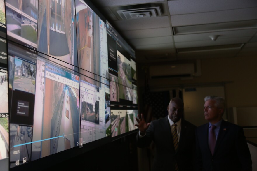 Suffolk County Police Commissioner Rodney Harrison explains to County Executive Steve Bellone how the "S.H.A.R.E." camera initiative works between local schools and the emergency command center.