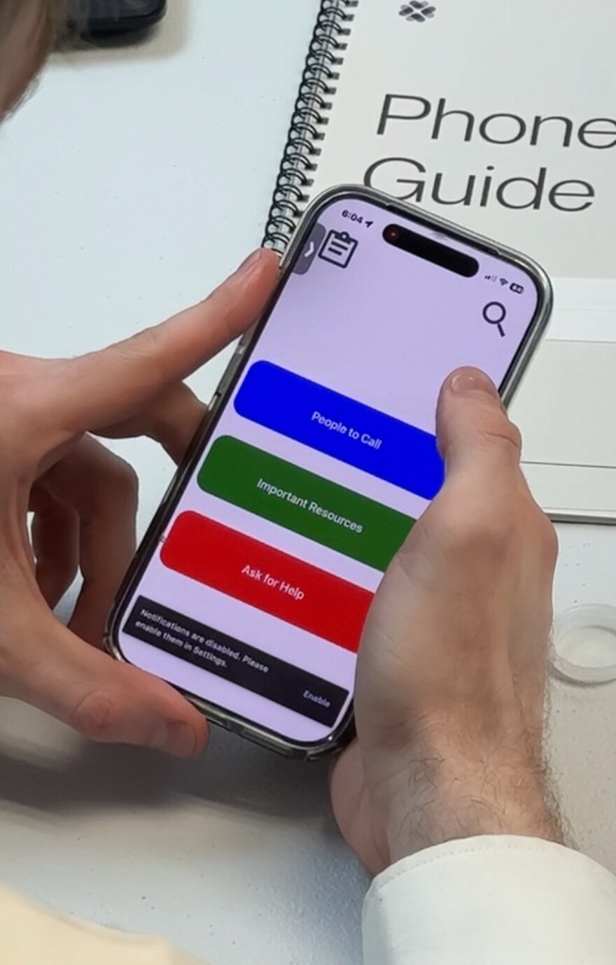 During the launch event, Dylan Carnahan demonstrates the app's features to a room of exonerees. There are 3 options to choose from. The top one is in blue, it reads, "people to call". The next one is in green, it reads, "important recourses". The last one says "ask for help". All of which you can press on and resources will appear.