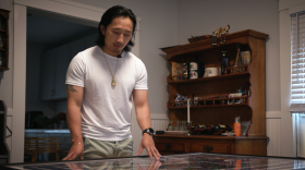 Johnny Kue examines a Hmong tapestry displaying the journey from Laos, to Thailand, to America.