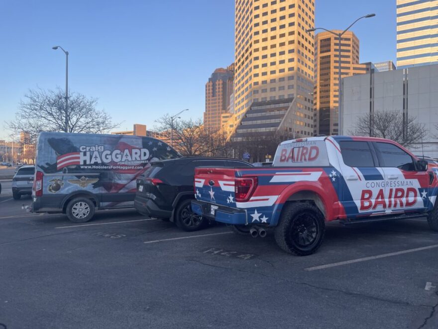Congressional campaign vehicles for U.S. House candidate Craig Haggard, a state representative, and sitting U.S. Rep. Jim Baird are parked next to the Indiana Statehouse on Wednesday, Feb. 18, 2026. Haggard's is a van with a flag on it reading "Craig Haggard." Baird's is a red, white and blue truck reading "Congressman Baird."