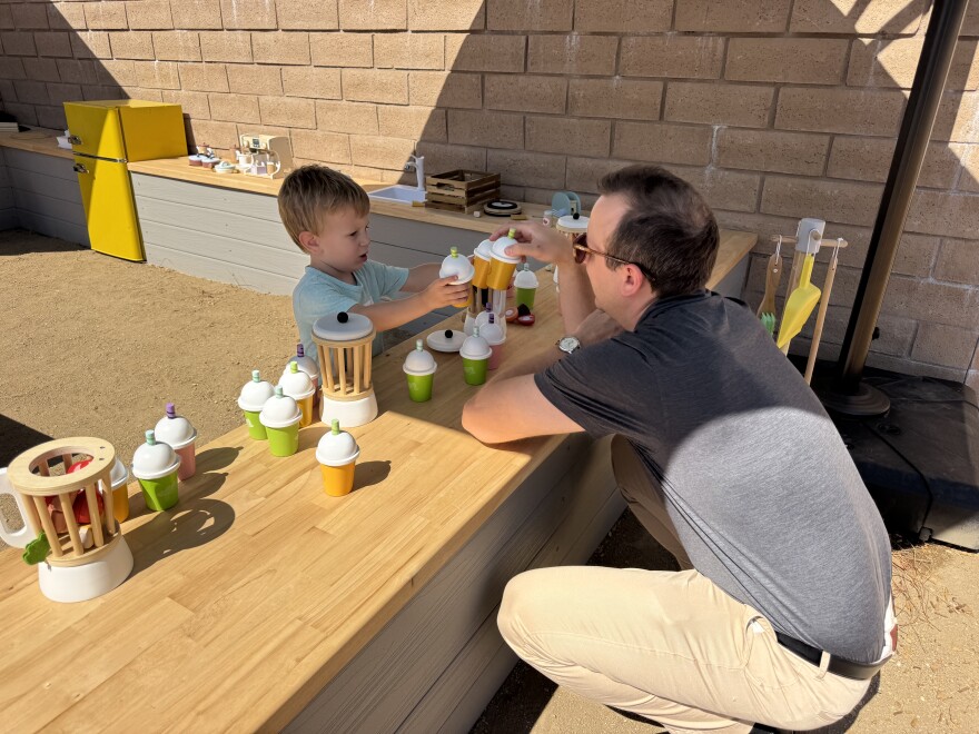 2-year-old Adam explores the outside play exhibits with his dad Nick