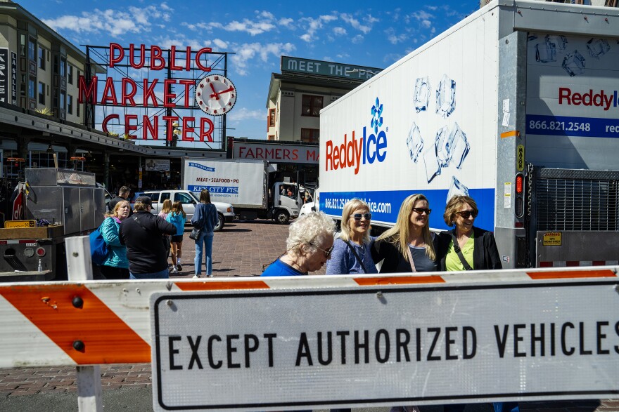 Temporary signs indicate a partial street closure at the intersection of 1st Avenue and Pike Street as part of a pilot program limiting cars driving through Pike Place Market on Fri., May 2, 2025.