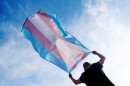 A young person holds a transgender pride flag.